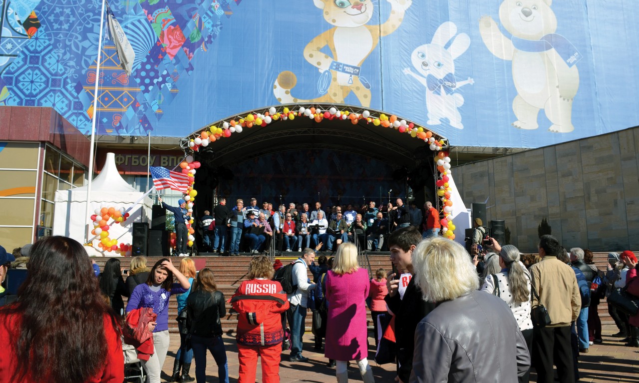 The men sing in the Mayor’s Park in Sochi with the official Olympic mascots providing.