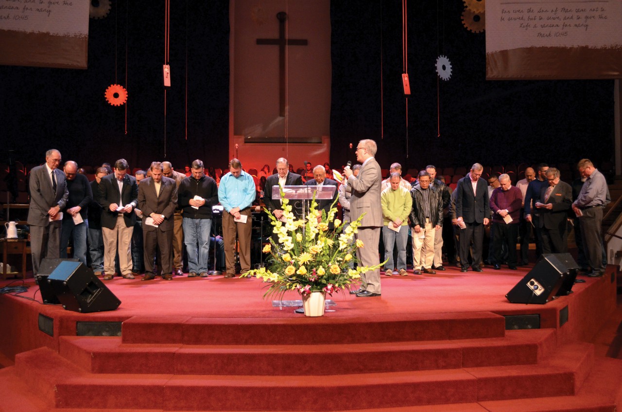 Evangelism Specialist Tim Gentry prays over All-State baptism leaders; SEC speakers included.