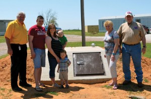 Cecilia Breedlove, second from right, and her grandchildren, Chris and Sarah Geddes and their sons, Zechariah and Christopher (Standing) are grateful for their new mobile home in Steelman Estates (In background at right) provided by the BGCO, represented by Porter, left, and Oil Patch Chaplaincy Consultant Tom Beddow, right. The BGCO also installed the new in-ground concrete storm shelter near their home. (Photo: Bob Nigh)