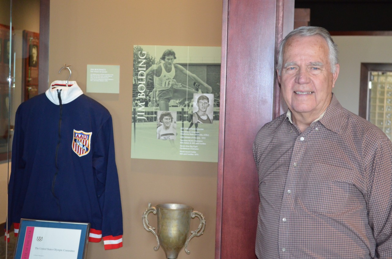 Gary Lower stands next to Jim Bolding’s exhibit at the Oklahoma Sports Hall of Fame. Lower coached the world track record holder in high school. 