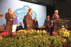 Hance Dilbeck, pastor of Oklahoma City, Quail Springs and newly-elected SBC 2nd vice president, with his wife, Julie, listen with newly-elected SBC President Ronnie Floyd, middle, to Frank Page, president and CEO of SBC Executive Committee, at podium, introduce the new SBC officers.
