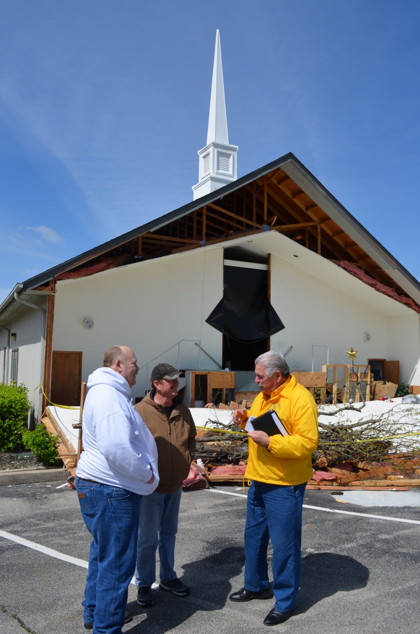    BGCO Disaster Relief Director Sam Porter, right, visits with, from left, David Healey and Larry Dyer, members of Sand Springs, Keystone Hills, which was severely damaged by a twister March 25. The church auditorium in the background is essentially a total loss, Dyer said. (Photo: Bob Nigh)