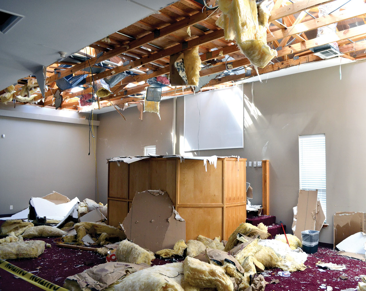 The interior of Sand Springs, Keystone Hills’ worship center shows the destructive force of the tornado that hit the building; 6) a member of a chain saw crew trims smaller branches off a huge tree which fell on a residence in Sand Springs. (Photo: Bob Nigh)