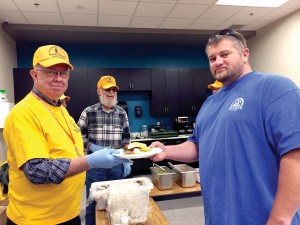 A job fair participant is served a hamburger from a DR volunteer.