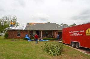 Disaster relief volunteers from Grady Baptist Association place tarps on the damaged roof of a home in Bridge Creek May 7. (Photo: Bob Nigh)