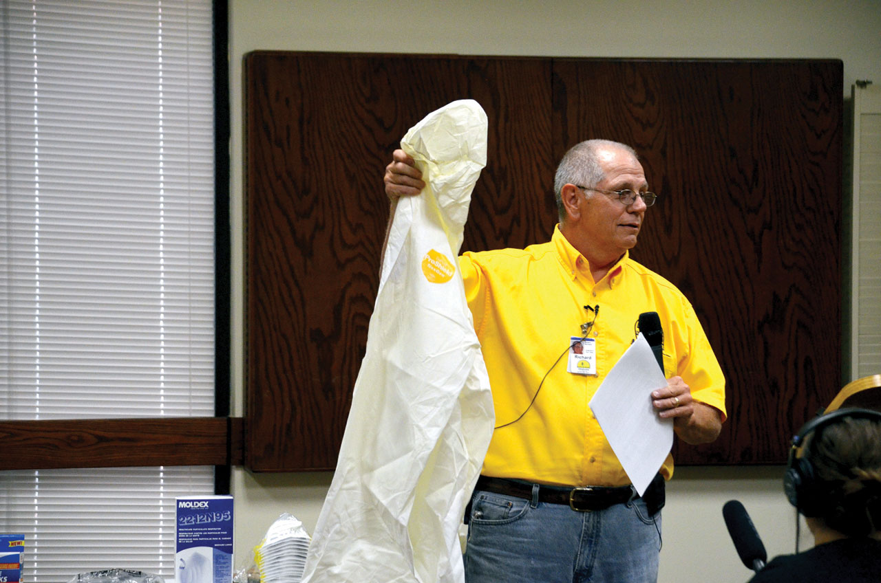 Mud-out and flood recovery expert Richard Brown displays a plastic clothing protection suit as part of his presentation during the first of three training sessions he gave May 27 at Norman, Bethel (Photo: Bob Nigh)