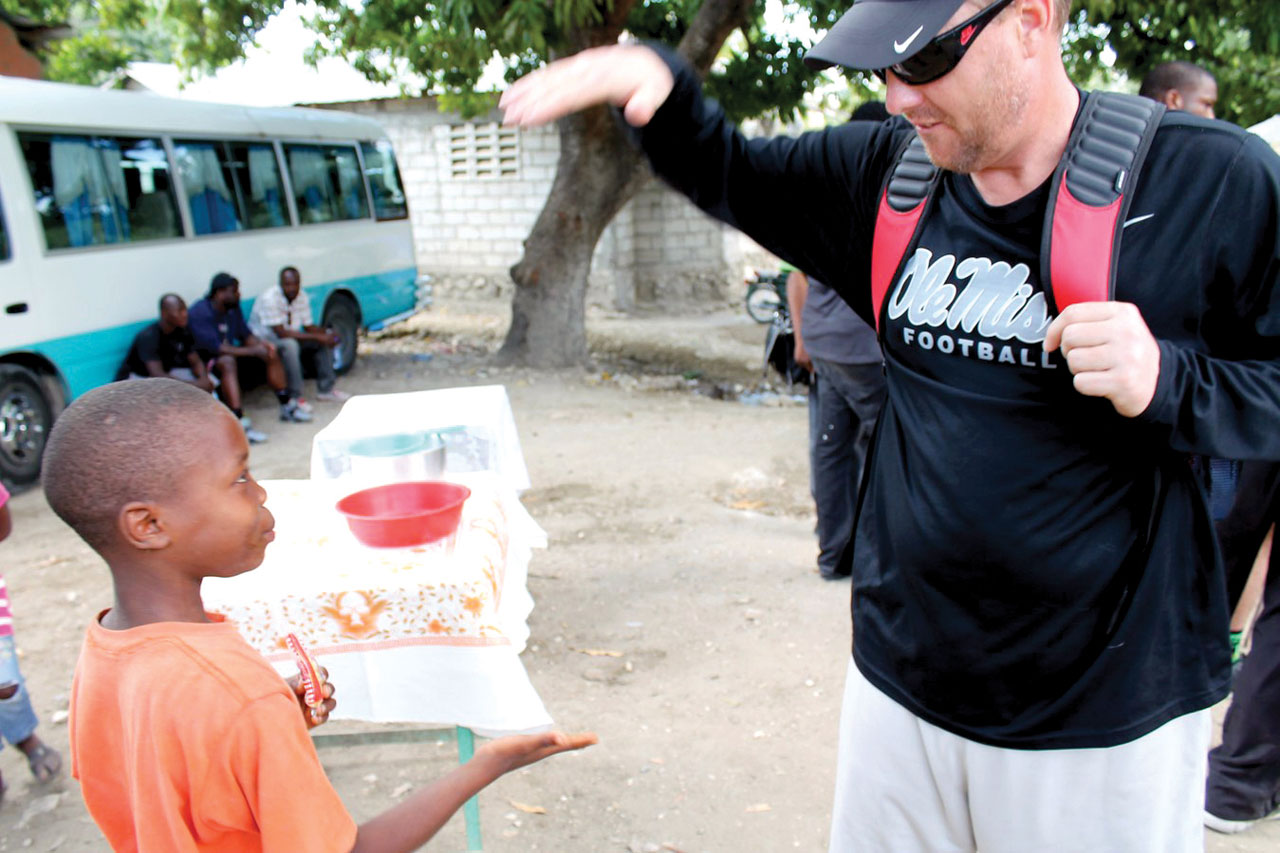 Ole Miss head football coach Hugh Freeze makes a new friend in Haiti during a mission trip joined by 11 players during this year’s Spring Break. (Photos: Baptist Press)
